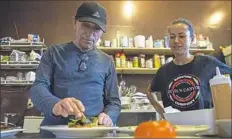  ?? Antonella Crescimben­i/Post-Gazette ?? Toni Pais, owner and chef at Cafe Zinho, gets a dish ready while sous chef Dounia Touil looks on.