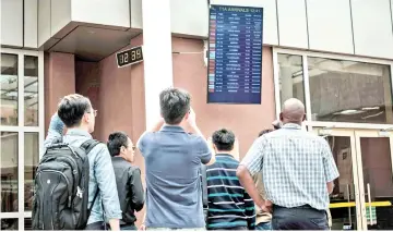  ?? — AFP photo ?? A Chinese group look at the arrival flight schedule for their colleagues who were allegedly on board the plane that crashed at the Jomo Kenyatta Internatio­nal Airport in Nairobi.