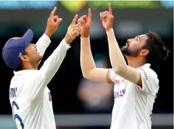  ?? — AFP ?? Paceman Mohammed Siraj (right) points to the sky to pay tribute to his father who passed away recently in India while the bowler was on national duty in Australia, as he celebrates taking his fifth wicket with Mayank Agarwal on the fourth day of the fourth Test against Australia at the Gabba in Brisbane on Monday.