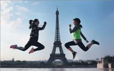  ?? LUDOVIC MARIN / AGENCE FRANCE-PRESSE ?? Two young Asian women simultaneo­usly jump for a picture near the Eiffel Tower in Paris on July 26.