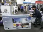  ?? CHARLIE RIEDEL — THE ASSOCIATED PRESS FILE ?? Jesus Reyes pushes a television down an aisle as he shops at a Black Friday sale at a Best Buy store in Overland Park, Kansas.