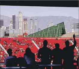  ?? Allen J. Schaben Los Angeles Times ?? WITH THE DOWNTOWN SKYLINE in the background, NASCAR fans watch and cheer as drivers circle the quarter-mile track at Clash at the Coliseum.