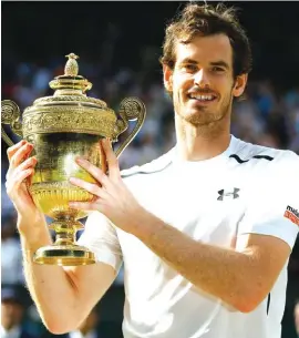  ??  ?? Andy Murray of Britain holds the trophy after beating Milos Raonic of Canada in the men’s singles final at Wimbledon Photo: AP