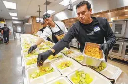  ?? HAYNE PALMOUR IV U-T FILE PHOTOS ?? Tony Moreno (right) and Jose Pablo plate salads as they and other O’side Kitchen Collaborat­ive volunteers prepare soup and salad dinners for seniors.