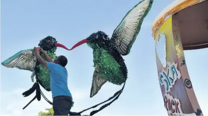  ?? PHOTOS BY KENYON HEMANS ?? Artist Jerome Marshall applies finishing touches to one of the four floats that was used in the Emancipati­on Day parade on Monday.