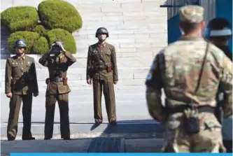  ??  ?? PANMUNJOM, South Korea: North Korean soldiers (left) look at the South side at the truce village of Panmunjom in the Demilitari­zed Zone (DMZ) on the border between North and South Korea.