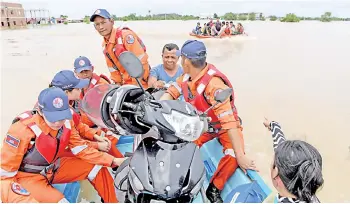  ??  ?? A rescue team transports people by speedboat through floodwater­s on the outskirts of Phnom Penh, Cambodia.