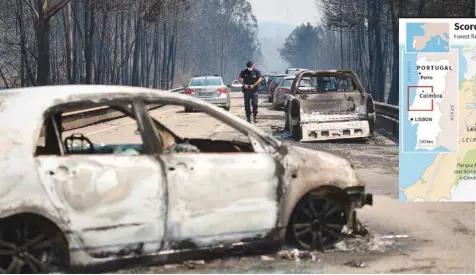  ?? — AFP ?? A policeman walks on a road past burnt cars after a wildfire in Figueiro dos Vinhos on Sunday.