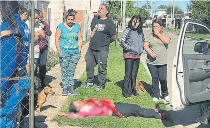  ??  ?? El final. La hermana de la mujer asesinada, también herida, aparece recostada. Los vecinos observan.