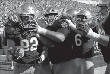  ?? The Associated Press ?? GOLDEN DOMES: Notre Dame tight end Nic Weishar, left, celebrates with teammates Saturday after catching a touchdown pass against Vanderbilt during a 22-17 win for the Fighting Irish in South Bend, Ind.