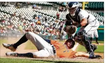  ?? GREGORY SHAMUS / GETTY IMAGES ?? Carlos Correa slides past the tag of Tigers catcher James McCann for a Houston run in the fifth inning Wednesday in Detroit. The Astros won 5-4.