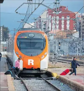  ?? ANNA MAS ?? Usuarios de Renfe cruzan la vía ante un tren de Rodalies.