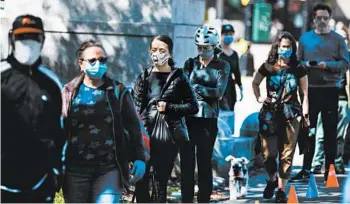  ?? DEMETRIUS FREEMAN/THE NEW YORK TIMES ?? A long line forms for face mask distributi­on May 2 at Prospect Park in the New York City borough of Brooklyn.