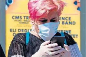  ?? EFE ?? Una mujer con guantes y mascarilla para protegerse del coronaviru­s mira su móvil, ayer, en el puente viejo de Murcia.