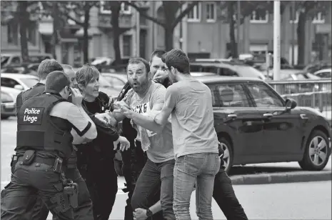  ?? GEERT VANDEN WIJNGAERT/AP PHOTO ?? Police try to calm a man at the scene of a shooting Tuesday in Liege, Belgium. A gunman killed three people, including two police officers, a city official said. Police later killed the attacker, and other officers were wounded in the shooting.