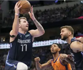  ?? TONY GUTIERREZ — THE ASSOCIATED PRESS ?? Dallas Mavericks’ Luka Doncic, left, leaps to shoot as Phoenix Suns’ Cameron Payne, center, and Mavericks’ Maxi Kleber, right, look on during the Mavericks playoff win Sunday.