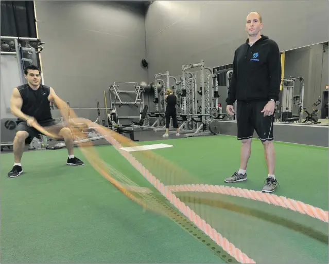  ?? PHOTOS: GLENN BAGLO/ PNG FILES ?? Physiother­apist Drew Teskey ( left) battles ropes at Studeo55’ s new location in downtown Vancouver as owner and head trainer Nathan Mellalieu looks on.