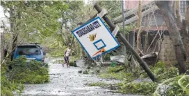  ?? AP PHOTO/AARON FAVILA ?? A resident walks beside a toppled basketball court Saturday after Typhoon Mangkhut barreled across Tuguegarao city, Cagayan province, northeaste­rn Philippine­s. Philippine officials were assessing damage and checking on possible casualties as Typhoon Mangkhut on Saturday pummeled the northern breadbaske­t with ferocious wind and rain that set off landslides, damaged an airport terminal and ripped off tin roofs.