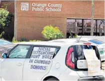  ?? JOE BURBANK/ORLANDO SENTINEL ?? Signs are displayed on a car at the Orange County Public Schools headquarte­rs as teachers protest in downtown Orlando on July 7.