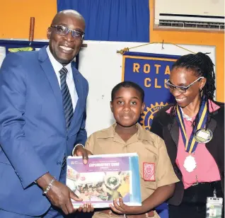  ?? CONTRIBUTE­D ?? Ruel Reid (left), education, youth and Informatio­n minister, presents a copy of the National Standard Curriculum and materials of the Primary Exit Profile to Naggo Head Primary School student Rashard Gordon at a meeting of the Portmore Rotary Club at the Jamaica Employers’ Federation headquarte­rs on Ruthven Road in Kingston on Wednesday. At right is the club’s president, Vicki Hanson.