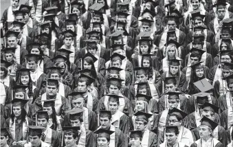  ?? File photo ?? Friendswoo­d High School students wait to graduate in June. The district no longer ranks students below the top 10 percent, hoping it’ll make colleges take a more holistic view of students.