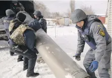  ?? VADIM GHIRDA, AP ?? Ukrainian emergency services employees push the remains of an S-300 missile fired by Russian forces onto a truck in Kharkiv, Ukraine, on Friday.