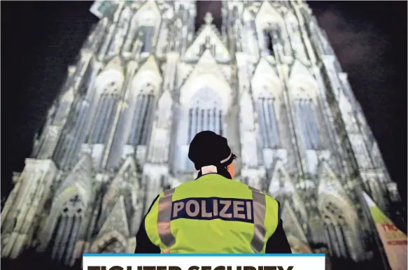  ?? PHOTOS BY OLIVER BERG, EUROPEAN PRESSPHOTO AGENCY ?? A police officer keeps watch at the Cologne Cathedral. Police will carry machine guns as security is increased.