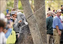  ?? AP ?? Tiger Woods hits an oak tree with his follow-through on his second shot at the par-4 16th hole Thursday. Woods saved par and was one of only 27 players in red numbers.