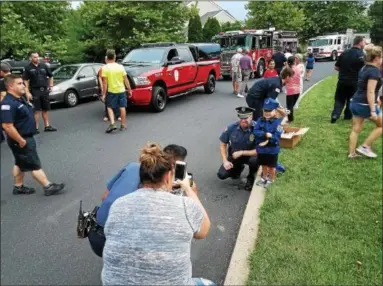  ?? DAN SOKIL - DIGITAL FIRST MEDIA ?? Upper Gwynedd Police Chief David Duffy, center left, poses for a photo with 4-year-old Harrison Rubinlicht as his mother Melissa takes a photo Tuesday during National Night Out celebratio­ns.