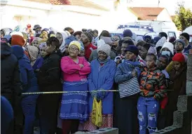  ?? ASSOCIATED PRESS ?? People stand behind a police cordon outside a nightclub in East London, South Africa, Sunday. South African police are investigat­ing the deaths of at least 20 people at a nightclub in the coastal town of East London early Sunday morning. It is unclear what led to the deaths of the young people, who were reportedly attending a party to celebrate the end of winter school exams.