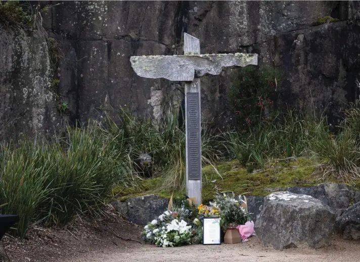  ??  ?? Flowers are left at the base of a cross that exhibits the names of victims at Port Arthur yesterday, as Australia marks the 25th anniversar­y of a lone gunman killing 35 people in Tasmania state in a massacre that galvanized the nation into tightening gun laws. Photo: AP