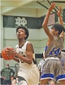  ?? STAFF PHOTO BY C.B. SCHMELTER ?? Notre Dame's DJ Brown drives past CSAS's Chase Pride (14) on Tuesday. Notre Dame won 54-33.