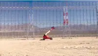  ?? (Defense Ministry) ?? WORKERS IN A ‘cherry-picker’ lend a sense of scale to the smart fence being installed around the country’s newest civilian airport currently under constructi­on.