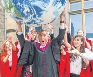  ??  ?? Honorary degree recipient Michael Palin holds up an inflatable globe alongside members of St Salvator’s Choir.