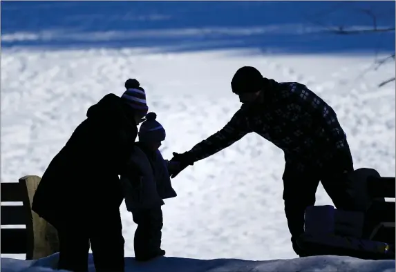  ?? AP PHOTO/MATT ROURKE ?? FILE - In this Feb. 5, 2021file photo, a couple helps a child on a snow covered embankment in Huntingdon Valley, Pa. The cost to adopt a child can range from $20,000to $45,000, according to the Child Welfare Informatio­n Gateway. Each year, millions of families navigate the expense and a process that can be overwhelmi­ng for prospectiv­e adoptive parents who aren’t familiar with the steps or fees involved.