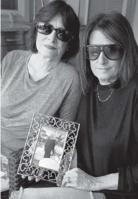  ?? CARLINE JEAN South Florida Sun Sentinel ?? Lori Helitzer, left, of Plantation and her sister Shari Wolf of Boynton Beach hold a picture of their mother Beverly Glass, 84, who died in March from the coronaviru­s.