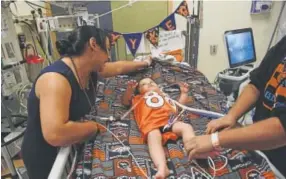  ?? Helen H. Richardson, The Denver Post ?? Tatiana Shibata comforts her son, Ryker, as her husband, Casey Christense­n, prepares him to go outside on his first birthday.