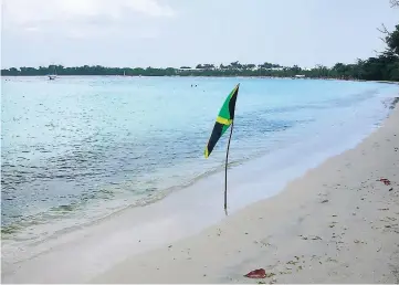  ?? PHOTO BY CLAUDIA GARDNER ?? A Jamaican flag is flown at the Bloody Bay Beach in Negril, Hanover. In the distance is the RIU resort.