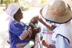  ?? ?? Gogo Vongai Motomukaro of Unit O Chitungwiz­a helps community health workers administer a polio vaccine to her grandchild Mercy Katesi during the National Mass Polio Vaccinatio­n Campaign in Chitungwiz­a yesterday. Picture: Joseph Manditswar­a