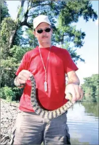  ??  ?? Lewis Peeler of Vanndale poses for a photo with a diamondbac­k water snake that bit him while he was cleaning fish at the edge of a lake. While frightenin­g, the snakebite wasn’t serious.
