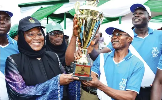  ??  ?? Acting Permanent Secretary, Federal Ministry of Education, Hajiya Hindatu Abdullahi (L), presents the winner’s trophy to Mr Aigboroga Aig Osbert, the leader of the Federal Ministry of Education team, which won the First Position in march past during...