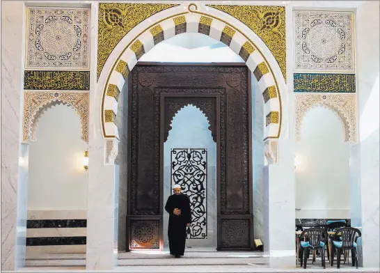  ?? Aileen Perilla ?? Orlando Sentinel Imam Khaliq enters the main prayer room of the building, which was built with 3 million pounds of white marble. Central Florida’s Muslim population is growing rapidly.