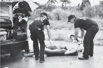  ?? INTERAKSYO­N.COM PHOTO ?? Police investigat­ors look over the bodies of two women murdered along with their male companion a few meters away, in what was made to appear to be a drug-related killing near the Daniel Z. Romualdez Airport in Tacloban City.