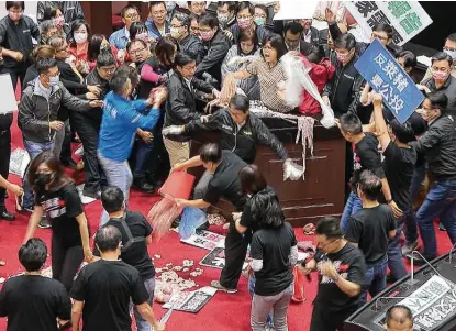  ?? Associated Press ?? In this image from video, members of the Nationalis­t KMT party dump pig guts on the floor of Taiwan’s parliament as a fight breaks out over allowing imports of U.S. pork and beef treated with ractopamin­e, a drug that produces leaner meat.