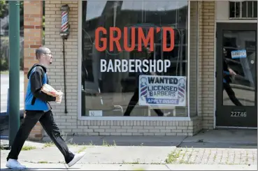  ?? TONY DEJAK — ASSOCIATED PRESS ?? A man walks past Grum’D Barbershop June 5 in Euclid. Ohio Gov. Mike DeWine announced Friday that casinos, amusement parks and racetracks will be allowed to reopen June 19.