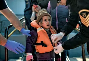  ?? AFP ?? A girl reacts as members of the Greek coastguard remove her life jacket after migrants arrived at Lesbos in Mytilene after crossing the Aegean sea from Turkey.—