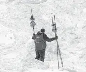  ??  ?? THE AREA where the avalanche on Mammoth Mountain occurred remained closed to visitors Sunday. Above, a Mammoth worker relocates markers.