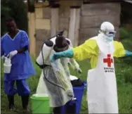  ?? AL-HADJI KUDRA MALIRO — THE ASSOCIATED PRESS ?? In this Sept. 9, 2018, file photo, a health worker sprays disinfecta­nt on his colleague after working at an Ebola treatment center in Beni, Eastern Congo. Sometimes violent community resistance is complicati­ng efforts to contain Congo’s latest Ebola outbreak, causing the rate of new cases to rise.