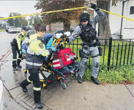  ?? DAN JANISSE ?? Paramedics and police wheel a man who sustained minor wounds from a police dog to hospital on Saturday.