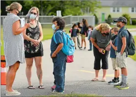  ?? SEAN D. ELLIOT/THE DAY ?? Principal Kristie Bourdoulou­s, left, greets students arriving for the first day of school Tuesday at Moriarty Environmen­tal Sciences Magnet School in Norwich. The city’s schools are opening on the hybrid model to start the year, with half the students attending in person on Mondays and Tuesdays, and the other half on Thursdays and Fridays. Buildings will be closed Wednesdays for deep cleaning, when all students will learn remotely.